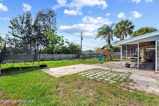 view of yard featuring a trampoline, a patio, and a sunroom