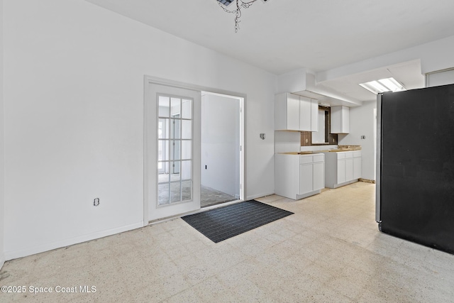315 Cherry Ave, Merritt Island, FL 32953 - kitchen with white cabinets, baseboards, and dark aggregate flooring