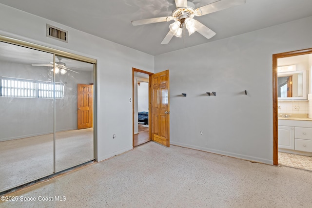 315 Cherry Ave, Merritt Island, FL 32953 - unfurnished bedroom featuring a closet, connected bathroom, speckled floor, a ceiling fan, and baseboards