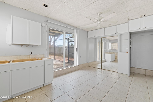315 Cherry Ave, Merritt Island, FL 32953 - kitchen with ceiling fan, light tile patterned flooring, white cabinetry, light countertops, and a drop ceiling