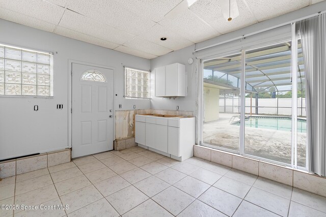 315 Cherry Ave, Merritt Island, FL 32953 - kitchen featuring light tile patterned floors, white cabinets, a drop ceiling, plenty of natural light, and light countertops