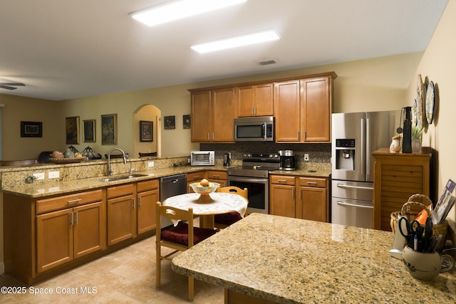 249 Franzing St, Palm Bay, FL 32908 - kitchen with appliances with stainless steel finishes, a sink, a peninsula, and brown cabinetry