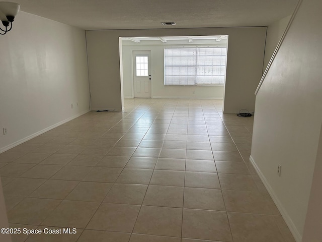 empty room featuring light tile patterned floors and baseboards