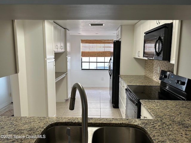 kitchen with black appliances, a sink, light stone countertops, white cabinets, and tasteful backsplash