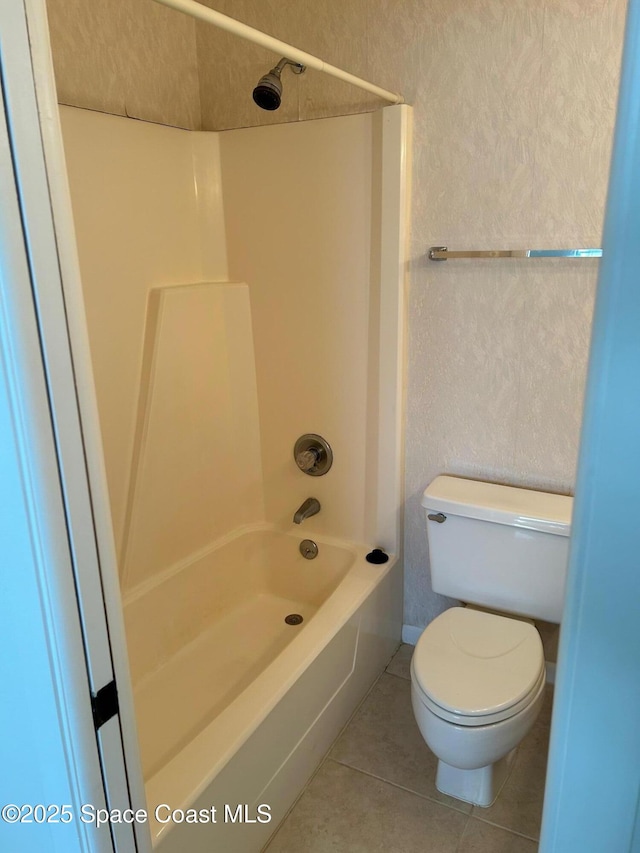 full bath with tile patterned flooring, toilet, shower / washtub combination, and a textured wall