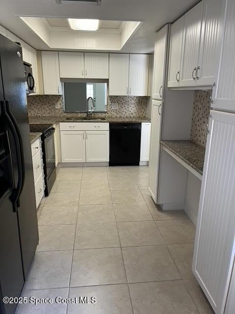 kitchen with black appliances, a raised ceiling, backsplash, and a sink