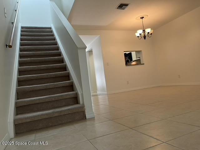 stairs with tile patterned floors, a chandelier, and baseboards