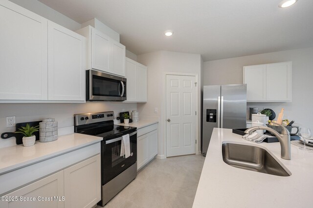 kitchen with a sink, white cabinetry, light countertops, and appliances with stainless steel finishes