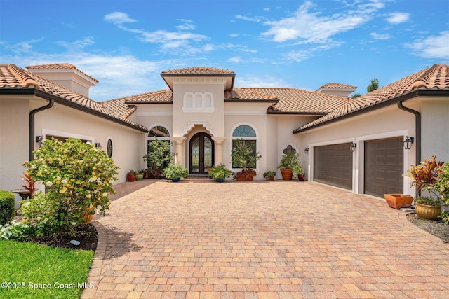 7346 Gorda Peak Ct, Melbourne, FL 32940 - mediterranean / spanish-style home featuring french doors, an attached garage, decorative driveway, stucco siding, and a tile roof