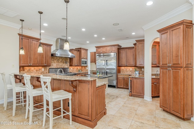 7346 Gorda Peak Ct, Melbourne, FL 32940 - kitchen with wall chimney exhaust hood, built in appliances, a peninsula, brown cabinetry, and recessed lighting