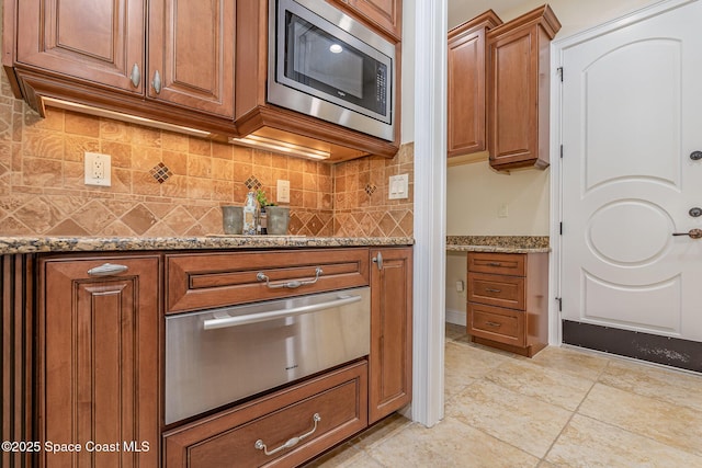 7346 Gorda Peak Ct, Melbourne, FL 32940 - kitchen featuring a warming drawer, stainless steel microwave, brown cabinets, and tasteful backsplash