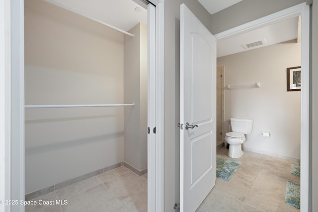 bathroom featuring toilet, visible vents, tile patterned flooring, baseboards, and walk in shower