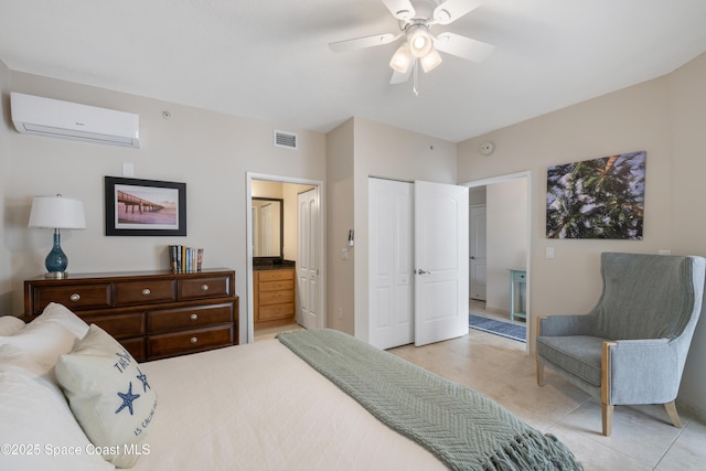 bedroom with a closet, visible vents, an AC wall unit, connected bathroom, and baseboards