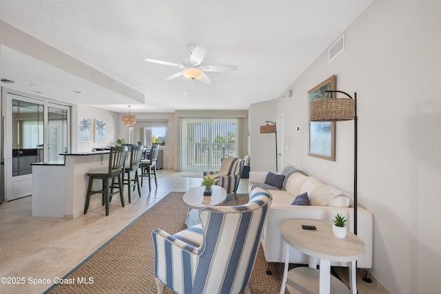 living area with light tile patterned floors, visible vents, and a ceiling fan