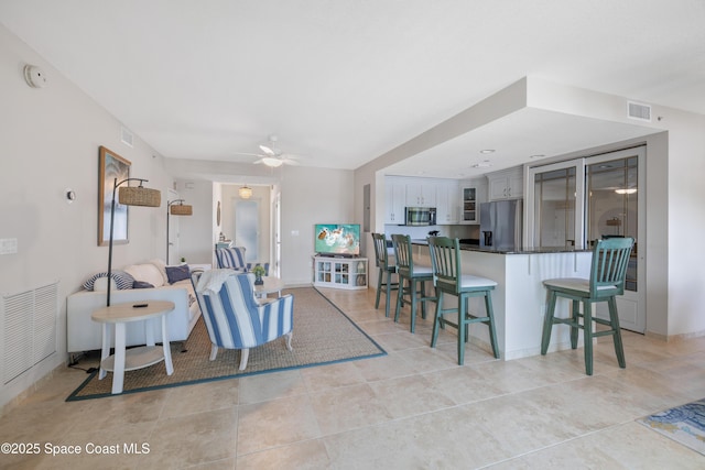 living room featuring visible vents, light tile patterned flooring, and ceiling fan