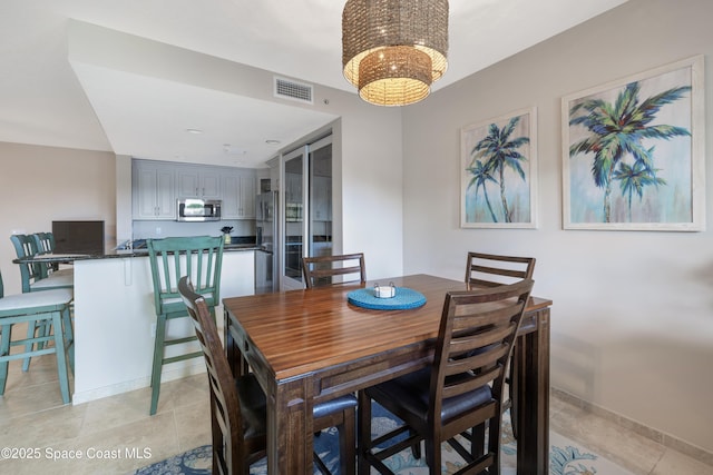 dining space with light tile patterned floors, baseboards, a chandelier, and visible vents