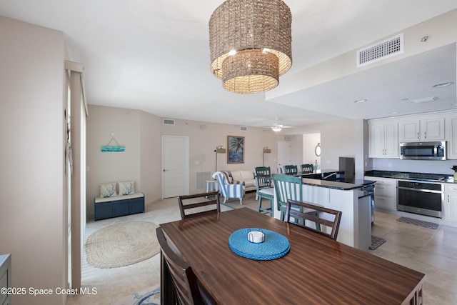 dining space featuring light tile patterned flooring, ceiling fan with notable chandelier, and visible vents