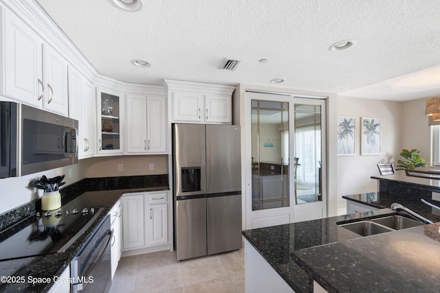 kitchen with glass insert cabinets, a sink, white cabinets, a textured ceiling, and appliances with stainless steel finishes