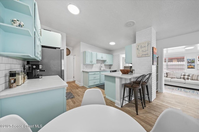 215 Jefferson Ave, Cape Canaveral, FL 32920 - kitchen with a sink, blue cabinets, open shelves, decorative backsplash, and light wood-style floors