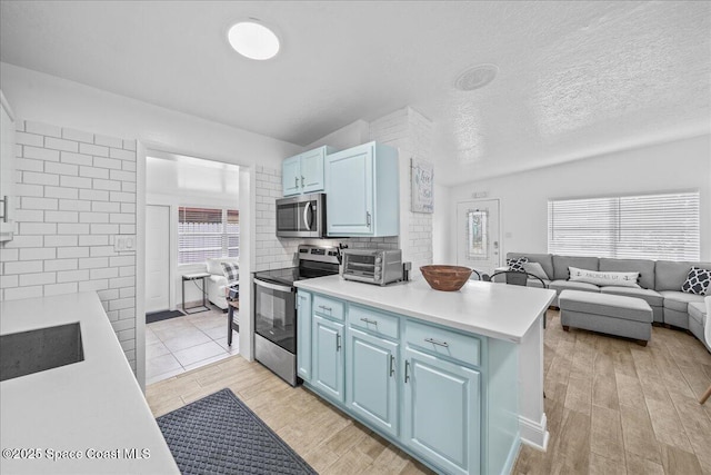 215 Jefferson Ave, Cape Canaveral, FL 32920 - kitchen with appliances with stainless steel finishes, blue cabinets, light countertops, and light wood finished floors