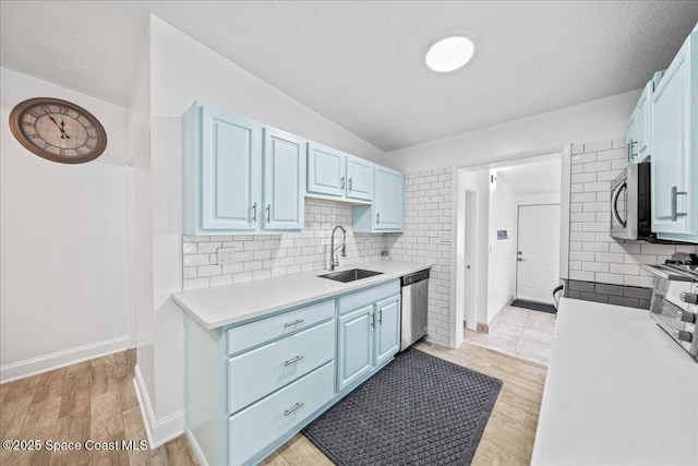 215 Jefferson Ave, Cape Canaveral, FL 32920 - kitchen featuring a sink, appliances with stainless steel finishes, blue cabinets, light countertops, and backsplash