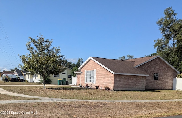 view of side of home featuring brick siding and roof with shingles