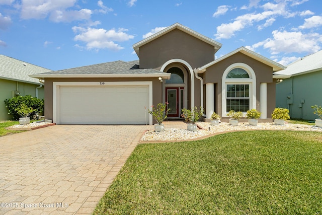 730 Sunset Lakes Dr, Merritt Island, FL 32953 - view of front facade with stucco siding, an attached garage, a front lawn, and decorative driveway