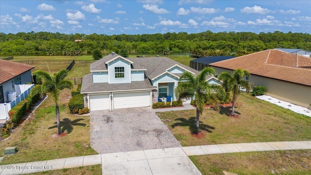 view of front of home with driveway, an attached garage, and a wooded view
