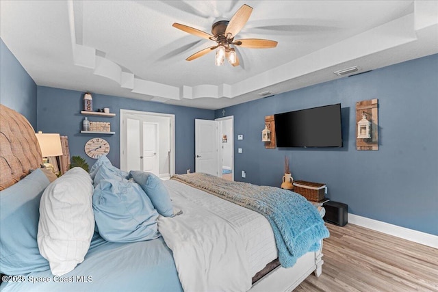 7268 Preserve Pointe Dr, Merritt Island, FL 32953 - bedroom with a tray ceiling, baseboards, light wood finished floors, and a ceiling fan