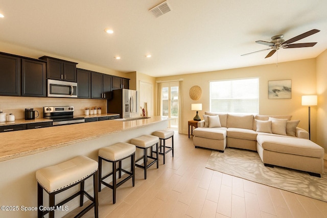 735 Sorrento Dr, Cocoa, FL 32922 - kitchen featuring stainless steel appliances, a kitchen bar, tasteful backsplash, open floor plan, and recessed lighting