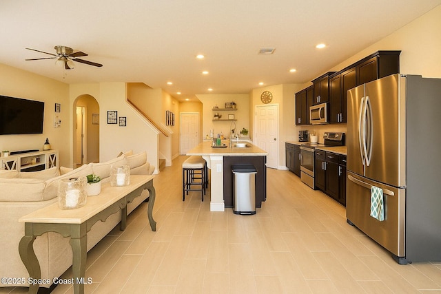 735 Sorrento Dr, Cocoa, FL 32922 - kitchen featuring stainless steel appliances, open floor plan, arched walkways, a breakfast bar, and light countertops