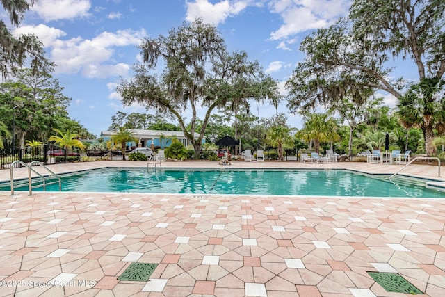 community pool with a patio area and fence
