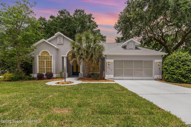 view of front of house with an attached garage, concrete driveway, a front yard, and roof with shingles