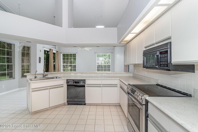 kitchen featuring black appliances, a sink, light countertops, backsplash, and light tile patterned floors