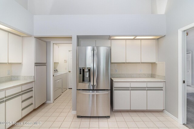 kitchen featuring stainless steel fridge, separate washer and dryer, light countertops, and light tile patterned flooring