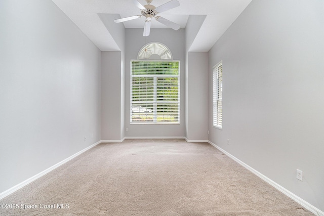 empty room with light colored carpet, a ceiling fan, and baseboards