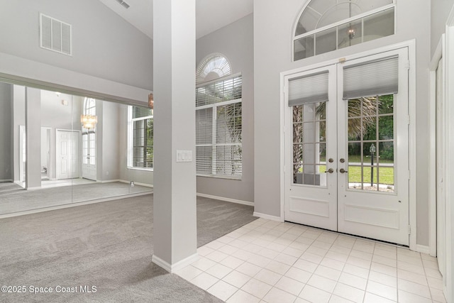 entryway with french doors, carpet, a towering ceiling, and baseboards