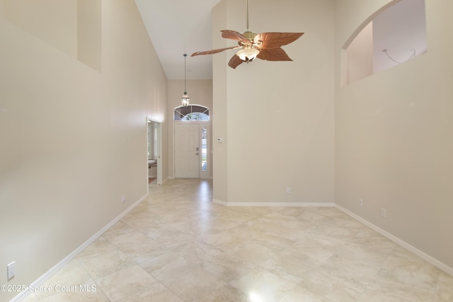spare room with high vaulted ceiling, a ceiling fan, and baseboards