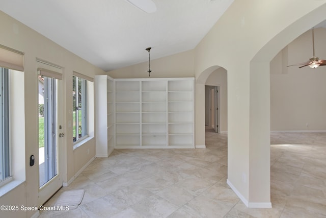 spare room featuring vaulted ceiling, ceiling fan, arched walkways, baseboards, and built in features