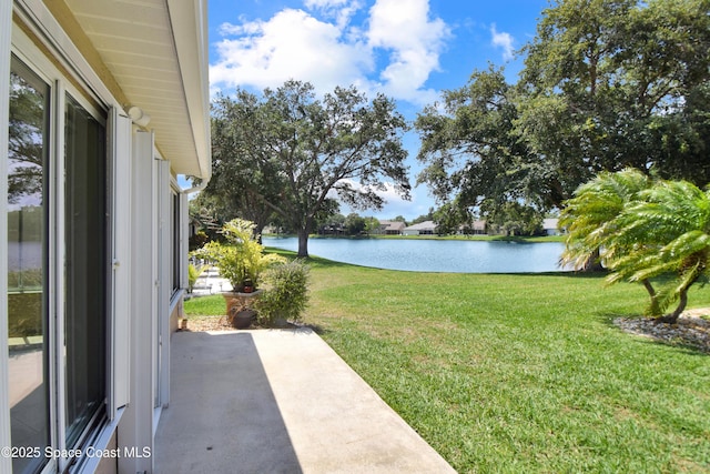 view of grassy yard featuring a water view and a patio area