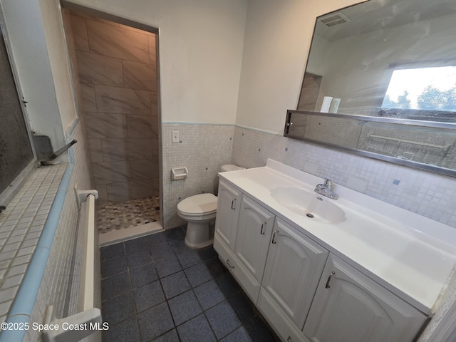 55 S Grandview Cir, Cocoa, FL 32922 - bathroom featuring vanity, tile patterned flooring, tiled shower, wainscoting, and tile walls