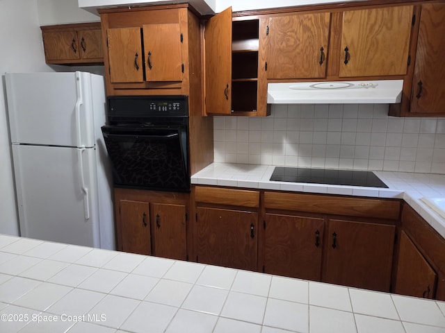 55 S Grandview Cir, Cocoa, FL 32922 - kitchen with black appliances, under cabinet range hood, backsplash, and brown cabinetry