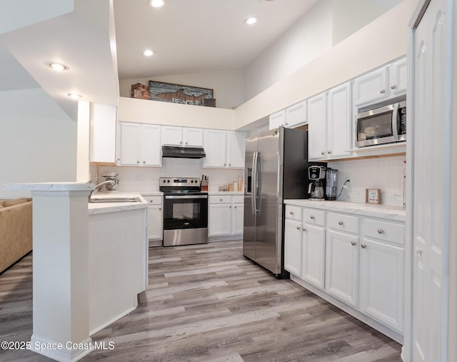 4920 48th Pl, Vero Beach, FL 32967 - kitchen with appliances with stainless steel finishes, under cabinet range hood, white cabinetry, light wood-style flooring, and light countertops