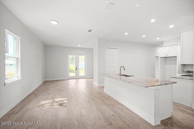 998 Wacona St SE, Palm Bay, FL 32909 - kitchen featuring a sink, recessed lighting, white cabinets, an island with sink, and light stone countertops