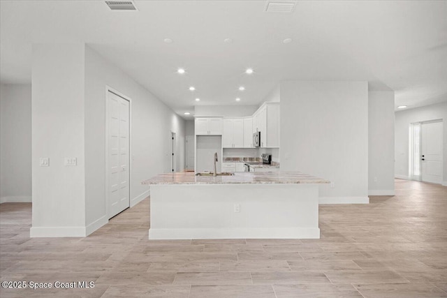 998 Wacona St SE, Palm Bay, FL 32909 - kitchen with white cabinets, stainless steel microwave, recessed lighting, a sink, and light stone counters