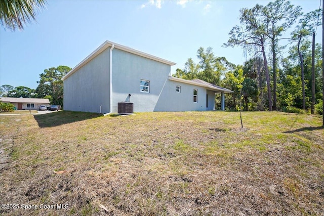 998 Wacona St SE, Palm Bay, FL 32909 - back of house with central AC unit, a yard, and stucco siding