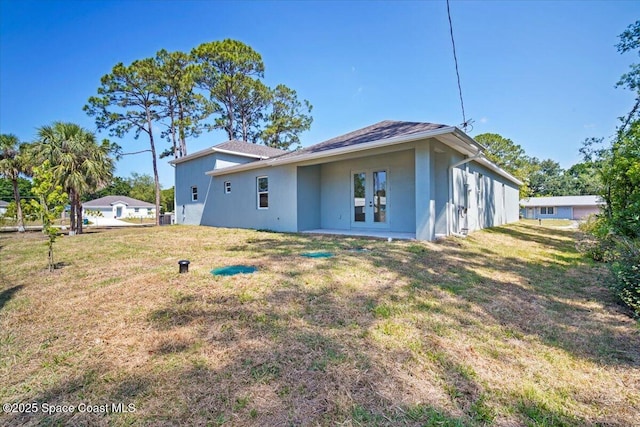 998 Wacona St SE, Palm Bay, FL 32909 - back of house featuring stucco siding, a lawn, french doors, and a shingled roof