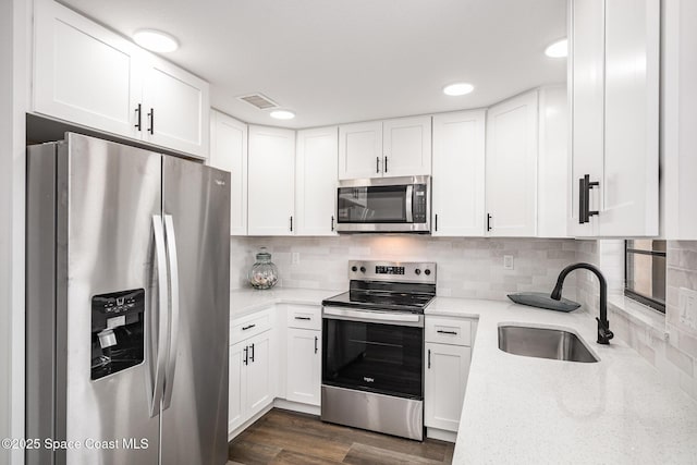 113 Harbor Dr, Cape Canaveral, FL 32920 - kitchen featuring appliances with stainless steel finishes, white cabinetry, light stone countertops, tasteful backsplash, and recessed lighting