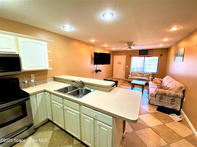 kitchen with stainless steel appliances, a sink, a peninsula, open floor plan, and a textured ceiling