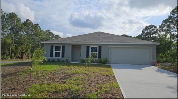 single story home with concrete driveway, an attached garage, stucco siding, and a front yard